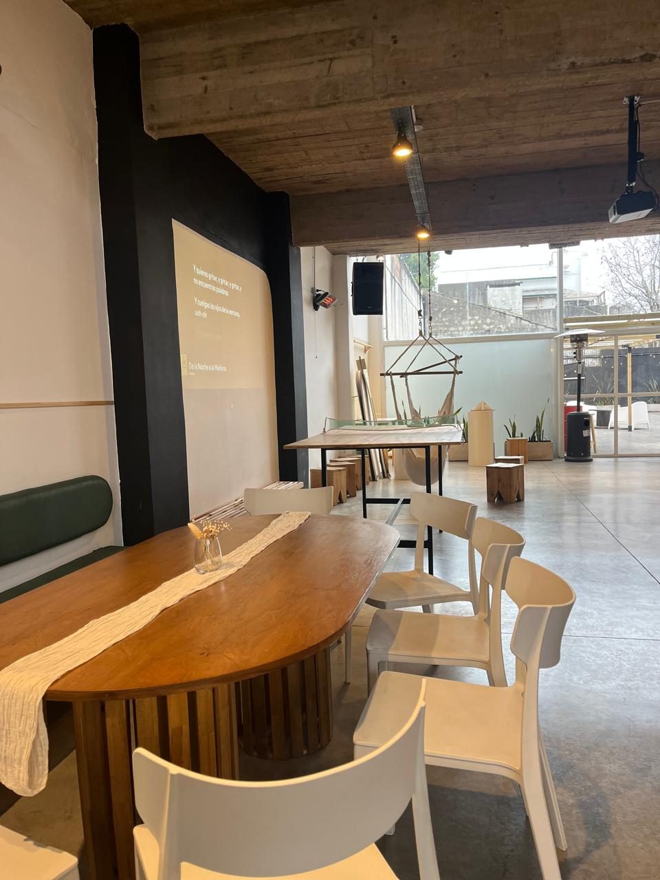 Mesa de madera con sillas blancas y la proyección sobre la pared