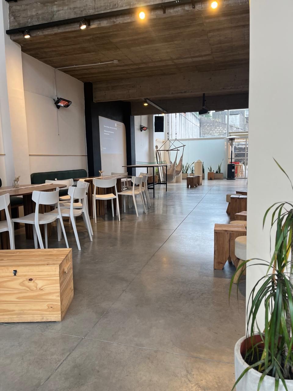 El salón de planta baja con mesas, banquitos de madera y la hamaca colgante al fondo